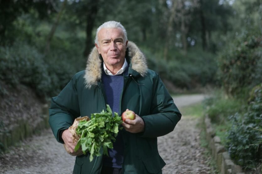 Man in Green Fur Coat Holding Vegetable and Apple Fruit