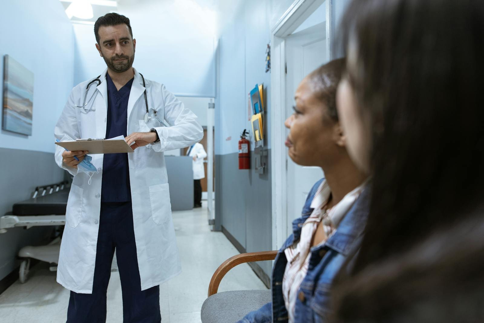 Man in White Medical Scrub Suit Standing Beside Girl in Blue Denim Jacket