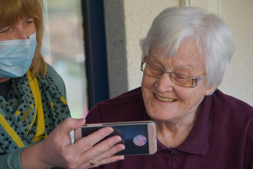 woman in brown button up shirt holding white smartphone